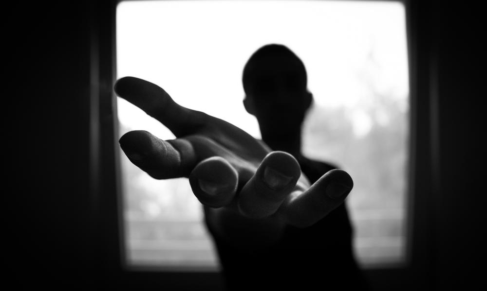 A backlit photo of a person extending a hand