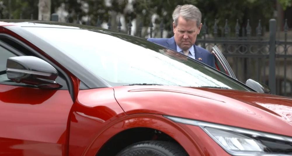 Governor Brian Kemp is shown getting into a red car.