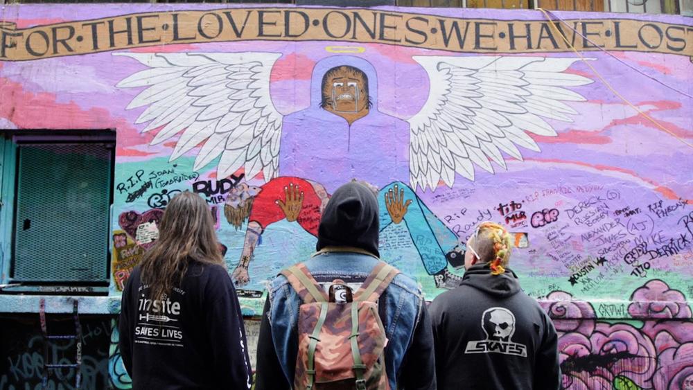 Three men standing in front of a mural.