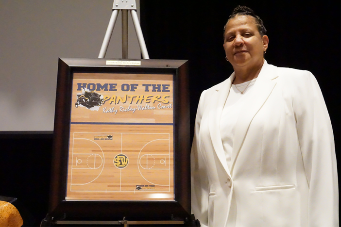 Southwest DeKalb Girls Basketball Coach Kathy Richey-Walton stands next to a plaque recognizing the re-naming of the school's basketball court in her honor.