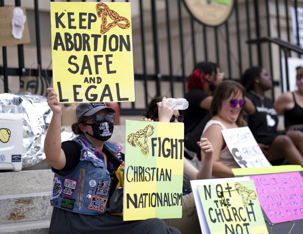 A small group, including Stephanie Batchelor, left, sits on the steps of the Georgia State Capitol protesting the overturning of Roe v. Wade on Sunday, June 26, 2022.