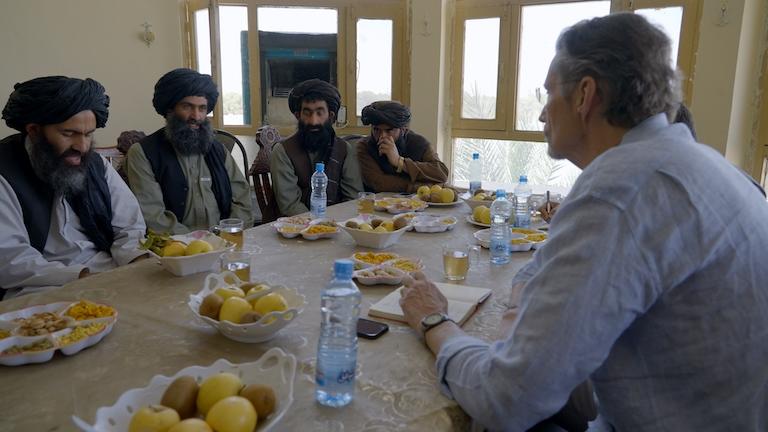 Five men sitting at a table talking.