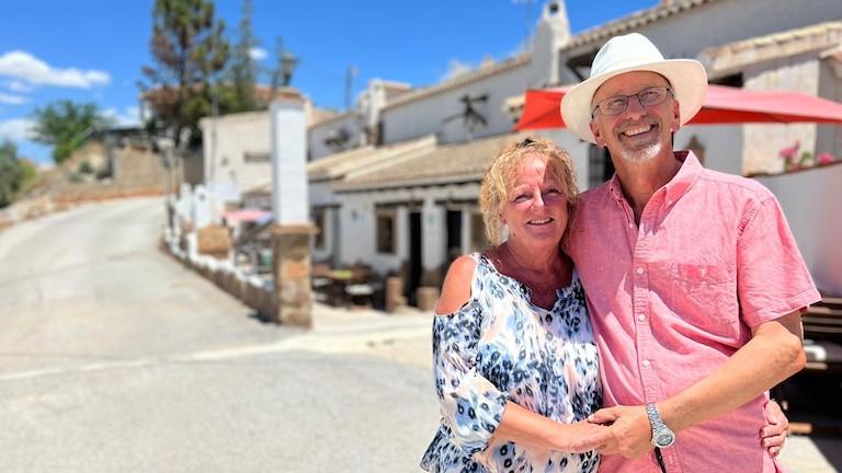 A man and woman hugging and smiling on a sunny street.