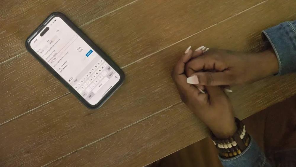 A cellphone on table with woman's hands