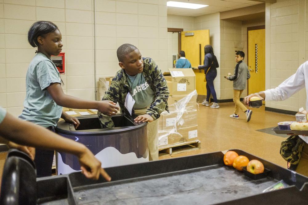 Ballard Hudson Middle School students Jalexia Maloy, left, and Jayden Parker, center, collect food during their lunch period in their roles as volunteer workers in the Helping Hands Ending Hunger program. 
