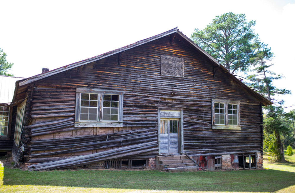 An old log cabin is shown in this daytime photo.