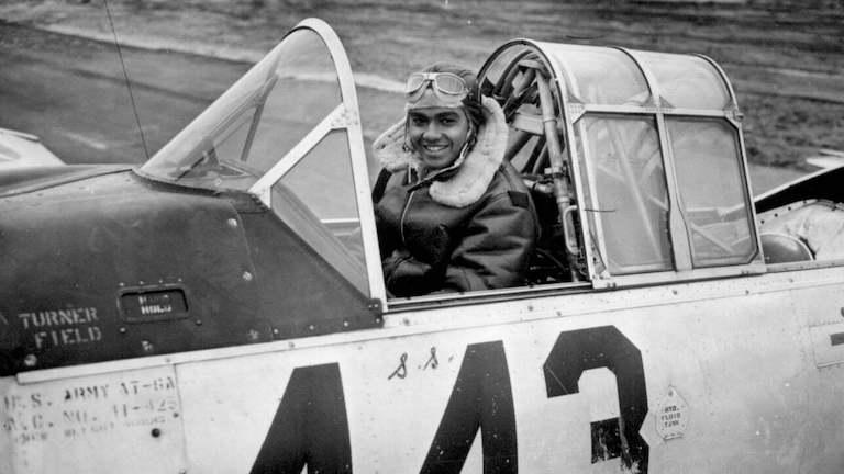 Black and white picture of a Tuskegee Airman in a plane.