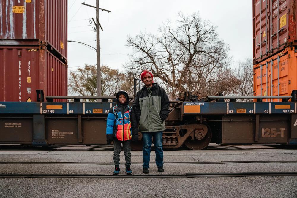  Jeremiah Johnson and his mother, Lamira Samson, climb over a parked freight train on their way to school. 