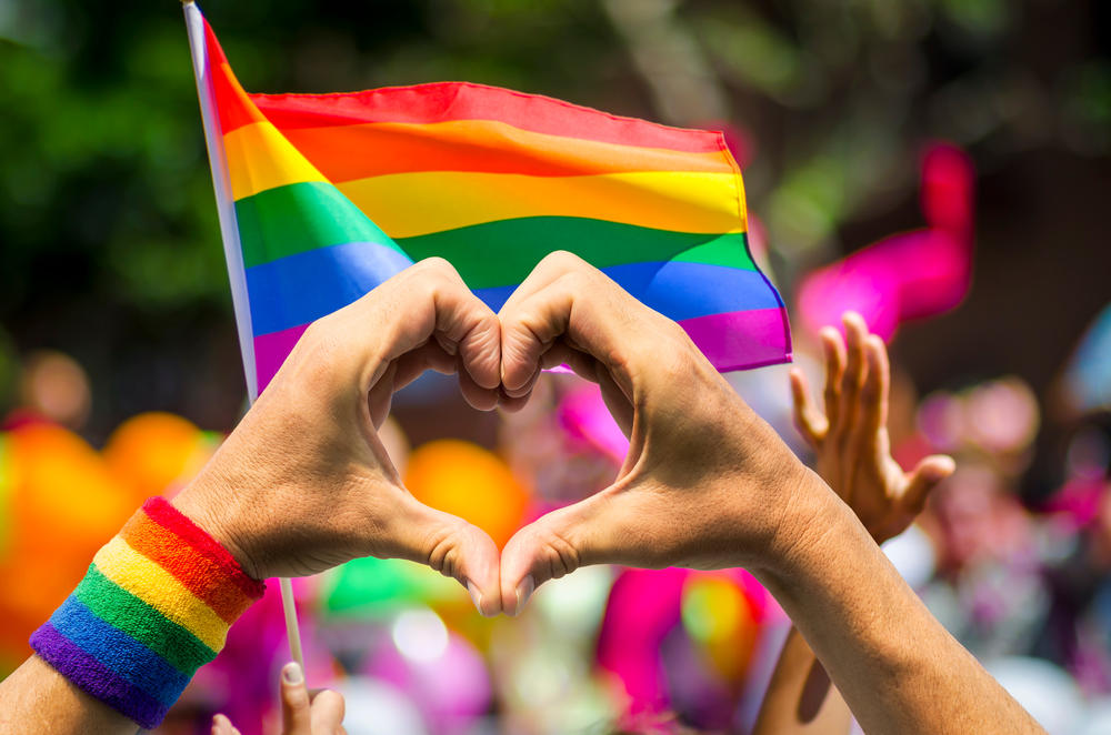 Love symbol with hands in front of a pride flag