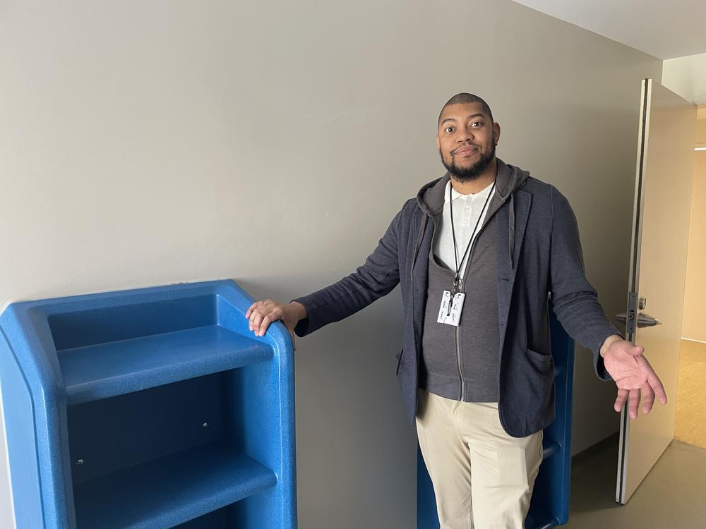 Anthony Long stands in front of a blue shelf botled to a patient room floor