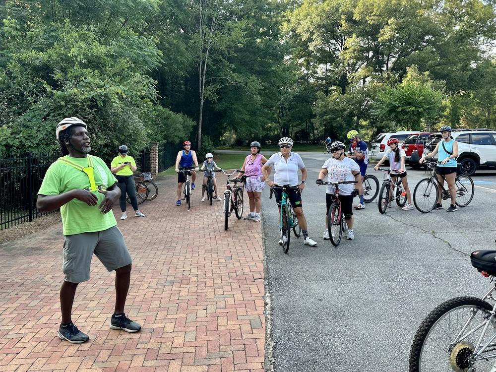Rudy Mendes, education program coordinator for Bike Walk Macon, instructs participants on bike safety at the Macon Bike Party Rivoli Roll group ride on June 8, 2023. Josephine Bennett / GPB.