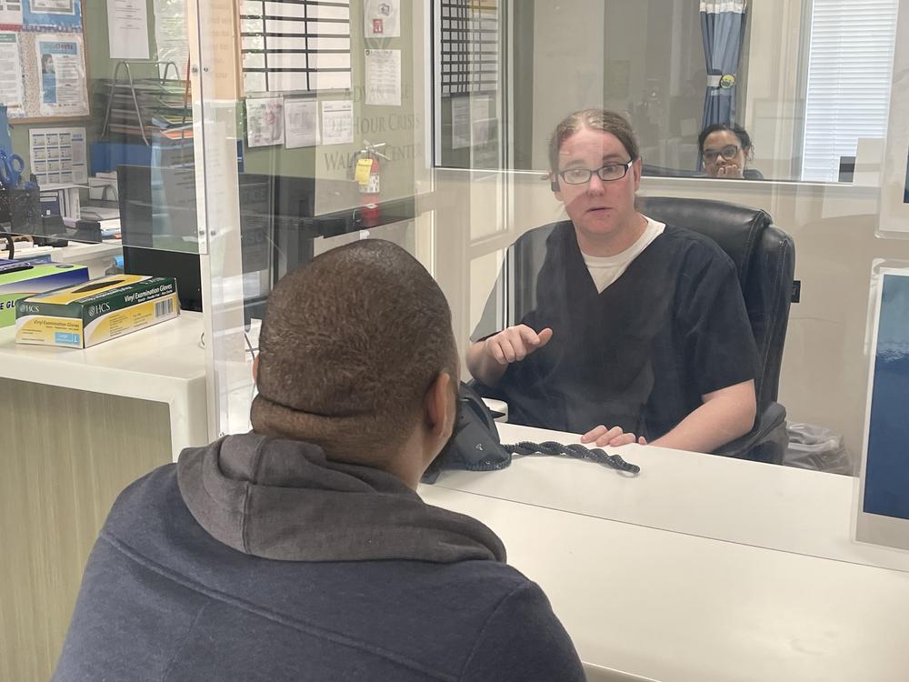 Justin Howell sits behind glass at the intake window at the Behavioral Health Crisis Center in Athens, Georgia.