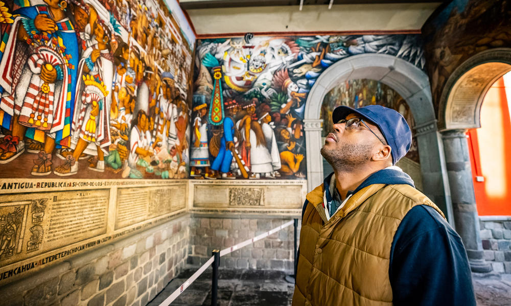 “Human Footprint” host Shane Campbell-Staton looking up at "The Gift of Maize" murals at the palace Of The Governor, Tlaxcala, Mexico.