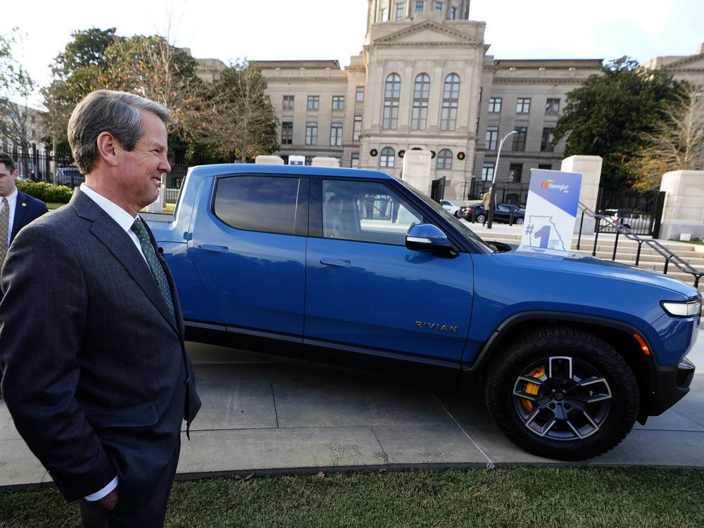 Gov. Brian Kemp smiles as he stands next to a Rivian electric truck during a ceremony to announce that the electric truck maker plans to build a $5 billion battery and assembly plant east of Atlanta projected to employ 7,500 workers, Thursday, Dec. 16, 2021, in Atlanta.