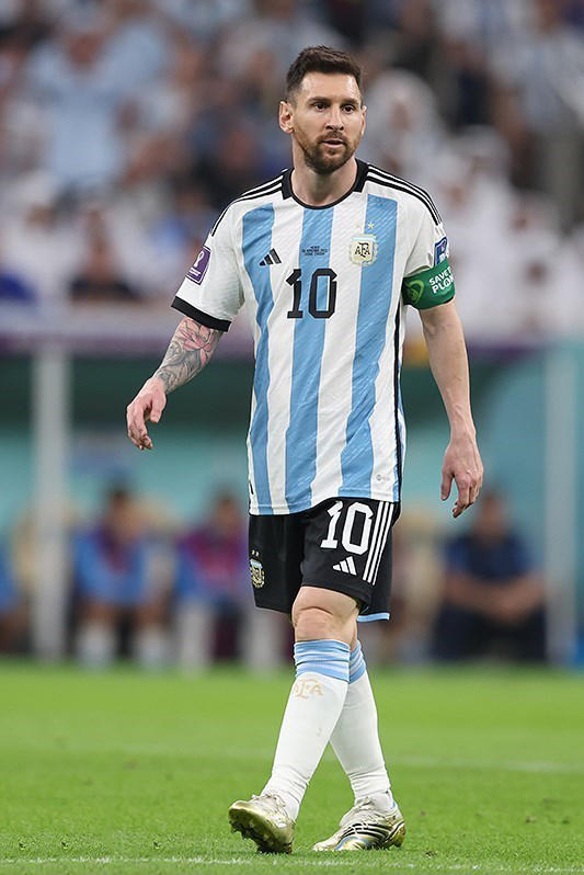 Argentine soccer play Lionel Messi is shown on a soccer field wearing a blue and white jersey.