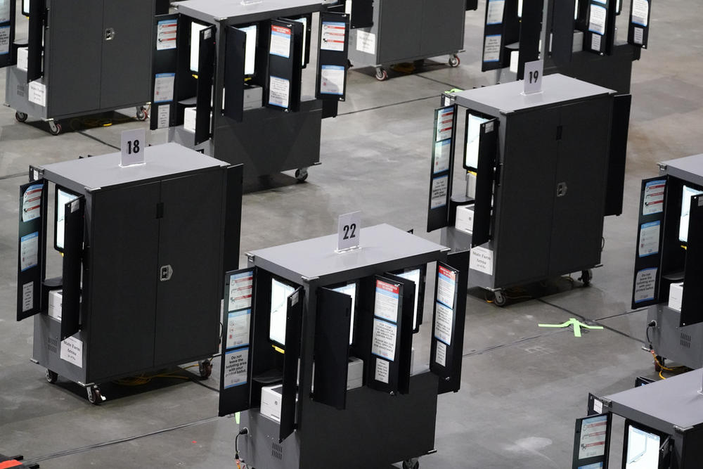 Voting machines fill the floor for early voting at State Farm Arena, Oct. 12, 2020, in Atlanta. Critics of the voting equipment used in Georgia say the state's plan to wait until after 2024 presidential election to install a software update meant to address flaws that an expert says leave the machines open to attack is irresponsible.