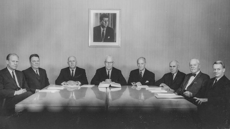 Men sitting around a table posed for a black and white photograph.