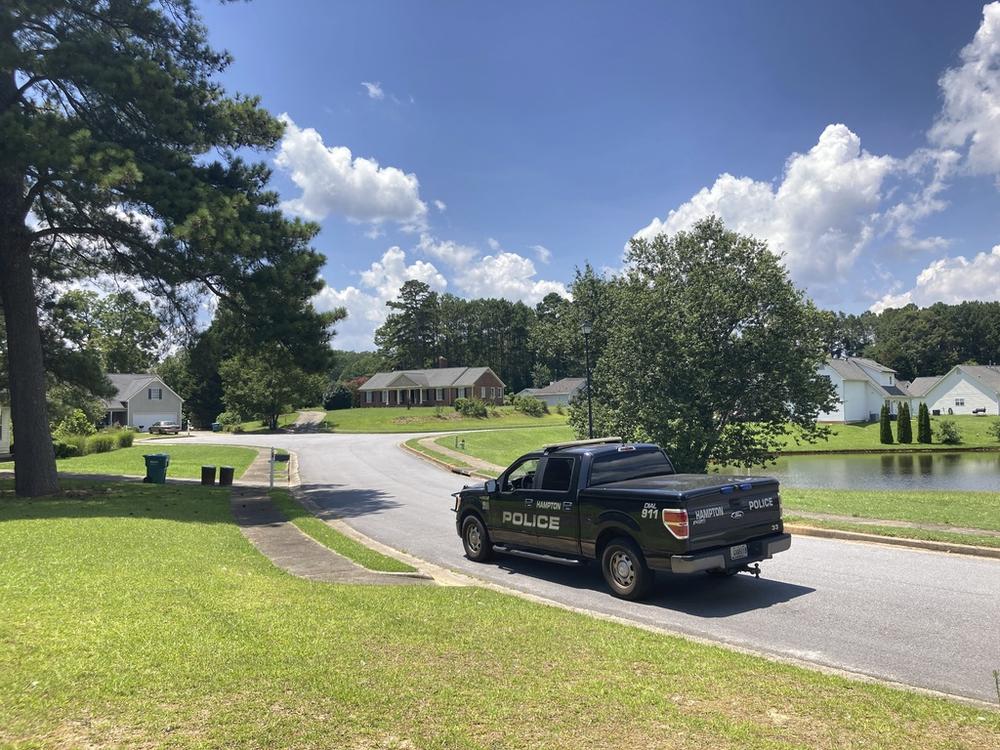 A police vehicle stands guard in the Dogwood Lakes neighborhood in Hampton, Ga., on Sunday, July 16, 2023. Police say a man who lived in the brick house in the background shot and killed four people in the neighborhood on Saturday, July 15.