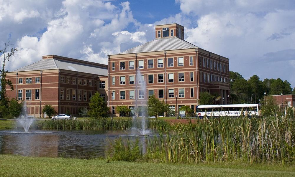 Georgia Southern University's main campus in Statesboro, with two academic buildings in the background and a pond with fountains and tallgrass in the background.