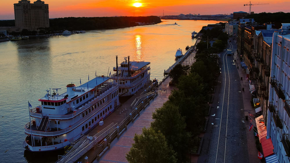 An aerial view of Savannah's River Street, with two riverboats docked along the Savannah River
