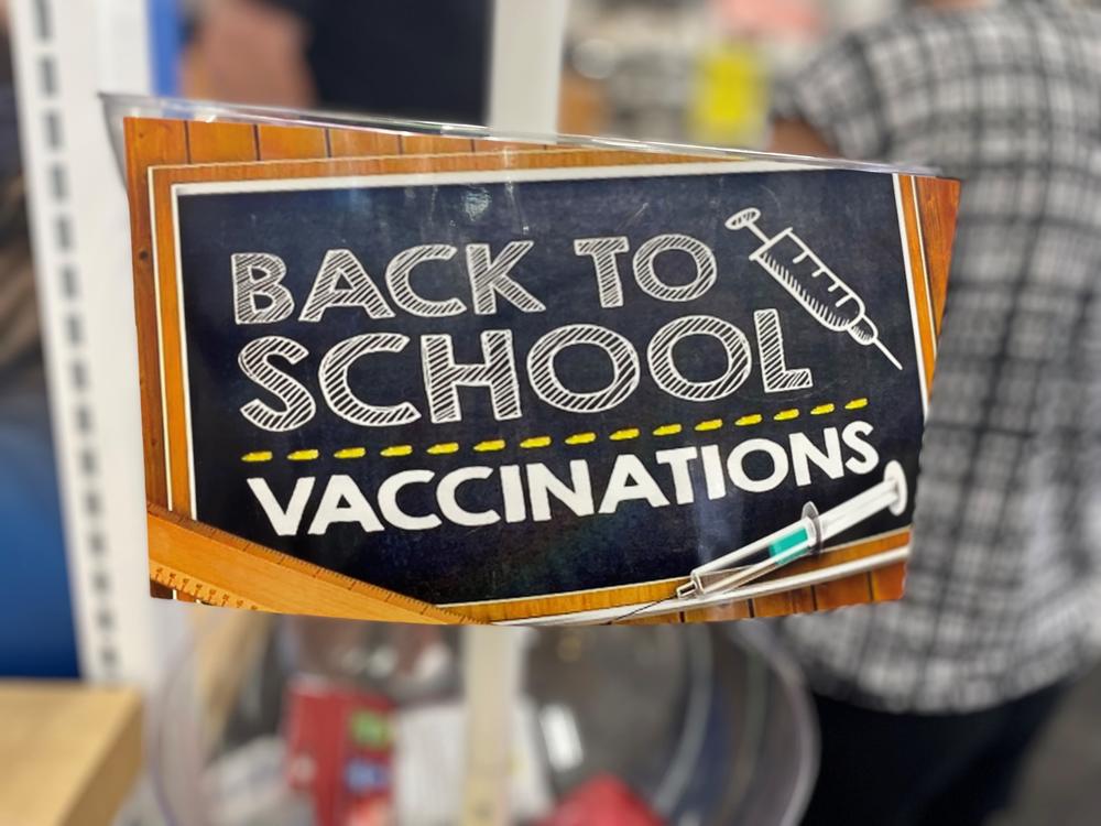 A sign saying "back to school vaccinations" in a pharmacy
