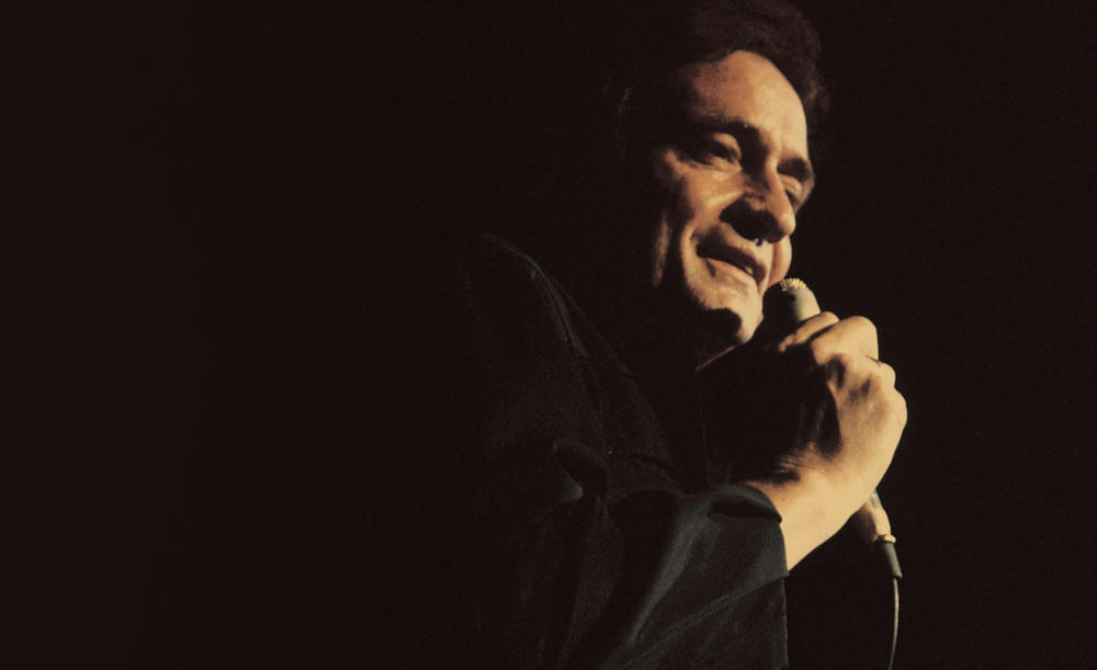 Johnny Cash on stage holding a microphone.