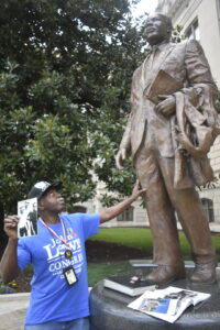 Singer and Civil Rights activist “General” Larry Platt shares photos and stories next to a statue of Martin Luther King Jr. at the Georgia Capitol. 