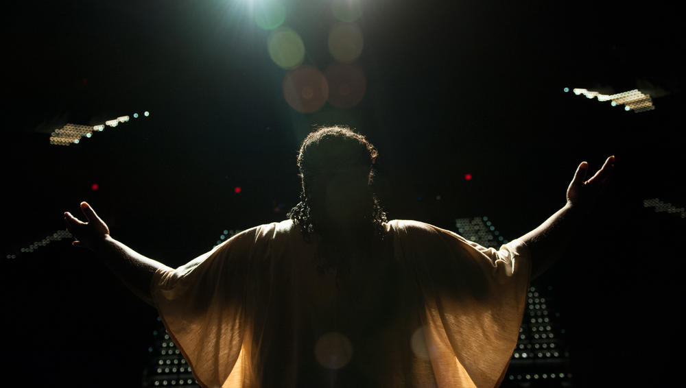 A woman with outstretched arms on a stage