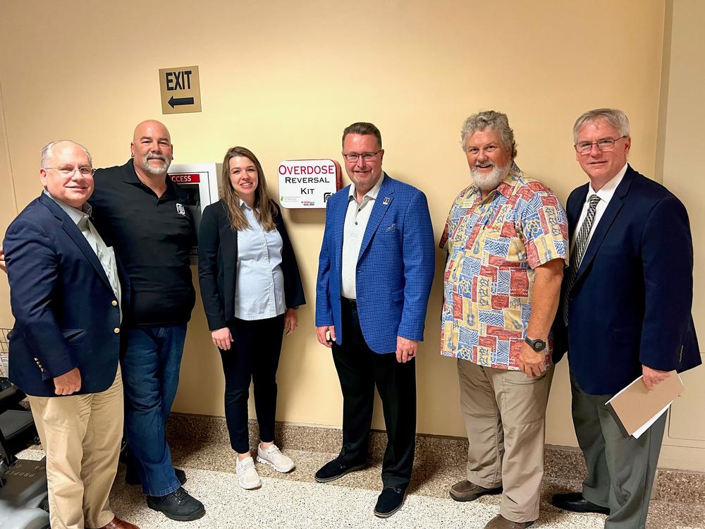 Six people stand next to an overdose reversal kit in the Georgia State Capitol