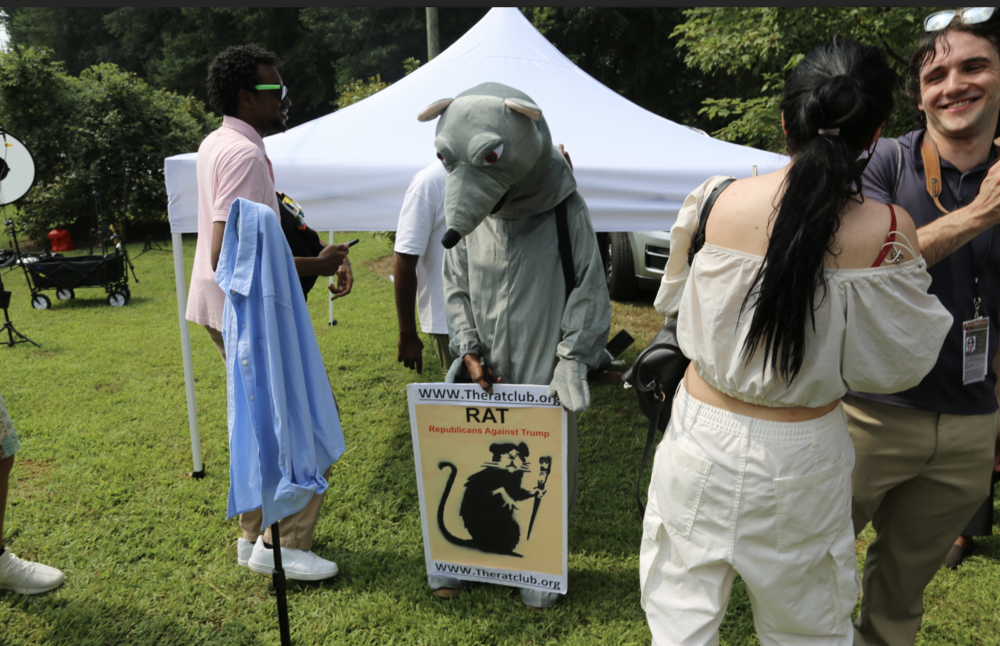 A woman in a rat costume carried a 'Republicans Against Trump' poster outside the Fulton County Jail on August 24, 2023.