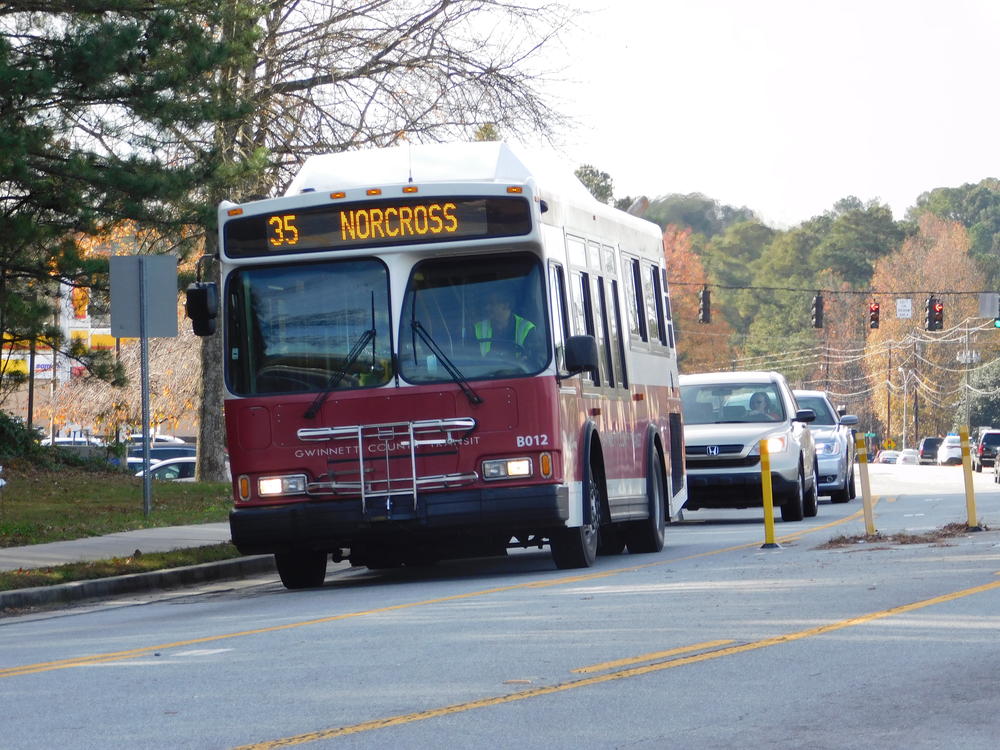 A red bus is shown traveling toward the camera.  Its sign reads "35 Norcross."