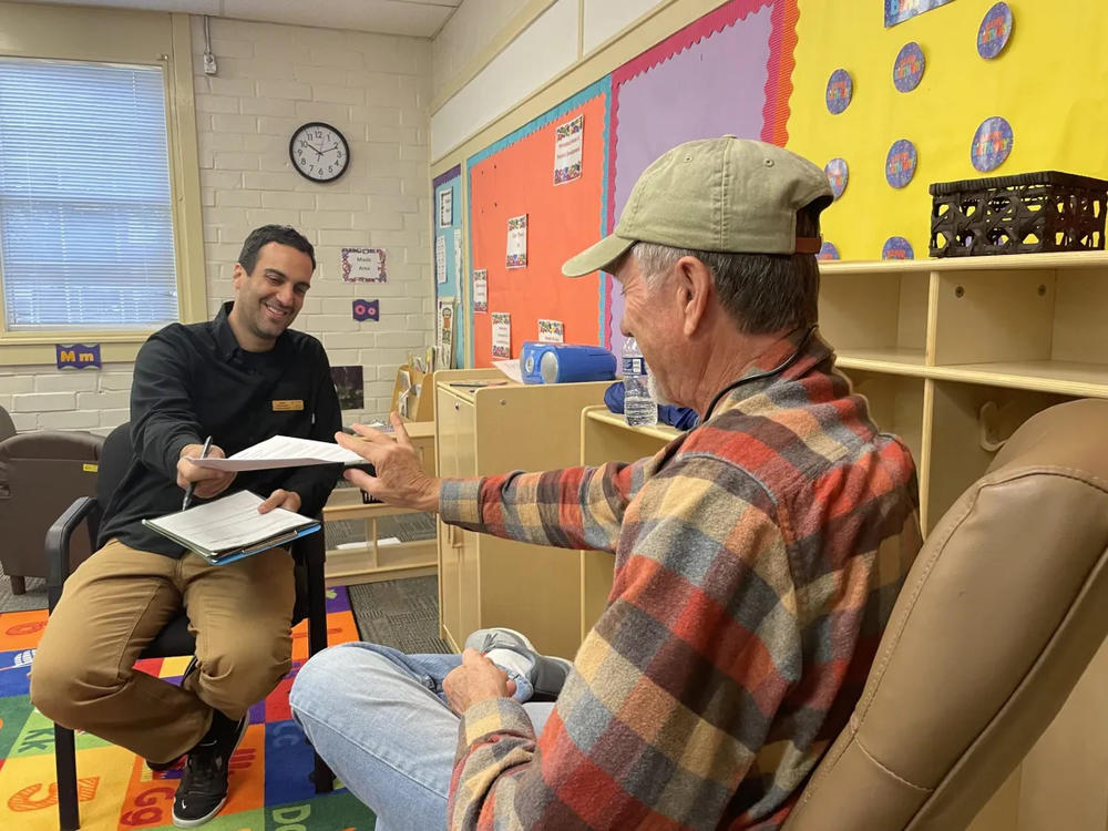 Noah Scovronick, assistant professor in the Rollins School of Public Health at Emory University and a co-leader of the study, hands a consent form to study participant Paul Christian in March 2023. 