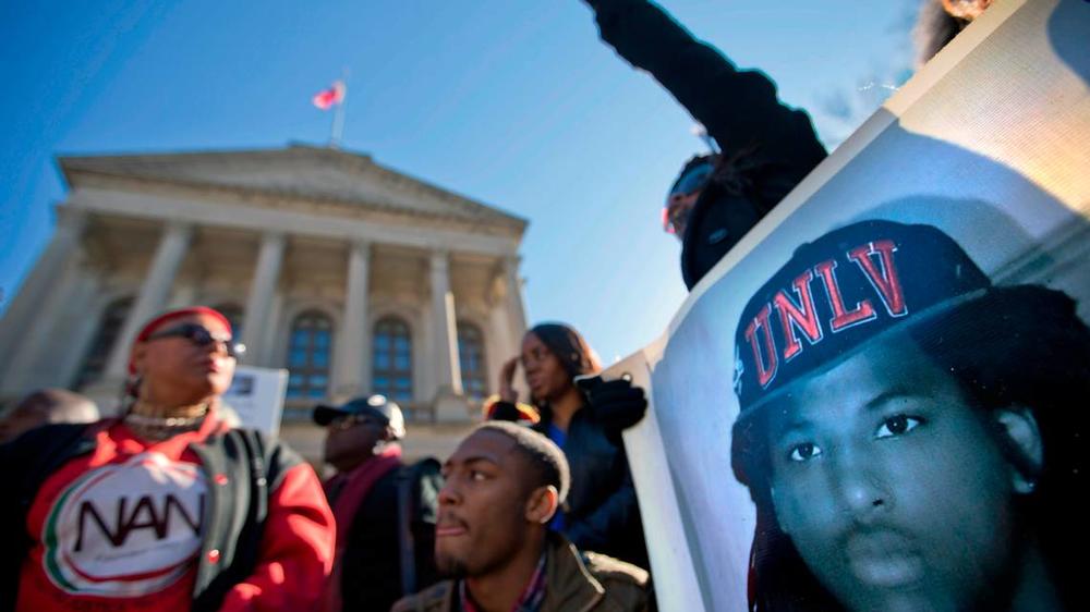 An image of Kendrick Johnson, the south Georgia teenager officials said was found dead inside a rolled-up wrestling mat in his school, is displayed on a banner, as demonstrators attend a “Who Killed K.J.” rally in Atlanta.