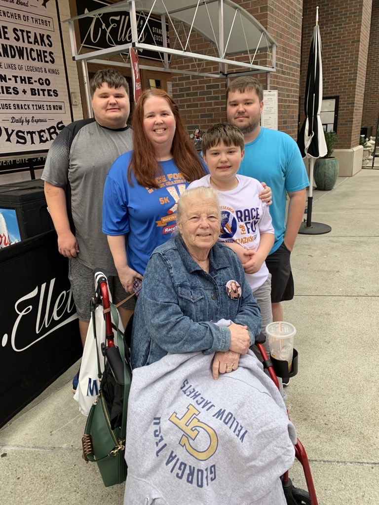 woman with red hair behind her mom in wheelchair and her three boys:  