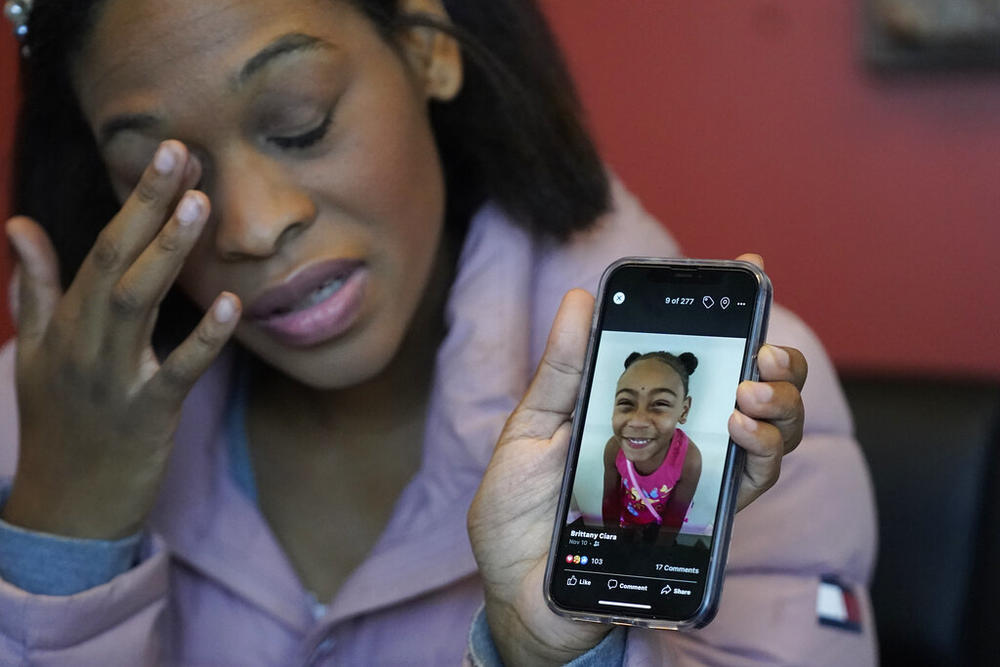Brittany Tichenor-Cox holds a cellphone with a photo of her daughter