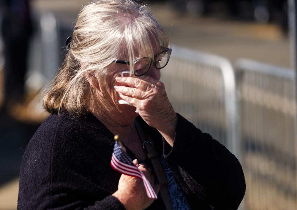 A bystander wipes away tears as Rosalynn Carter's funeral procession passes. 