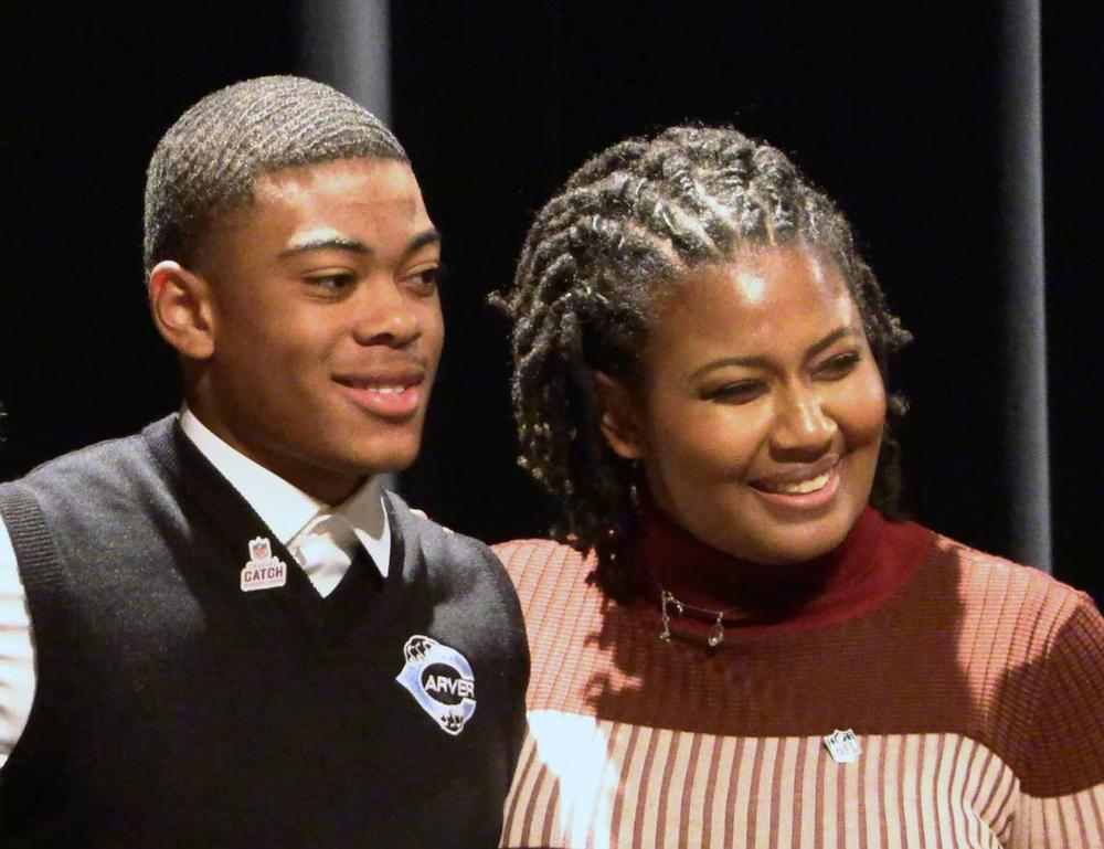 George Washington Carver High School junior Braylon Jakes, left, learned during Friday’s assembly that the NFL is providing two tickets for him and a guest to attend Super Bowl LVIII in Las Vegas. He was nominated by Kalin Tate, right, a 2014 Shaw High School graduate who is the NFL’s sponsorship coordinator. 11/03/2023 Mike Haskey 