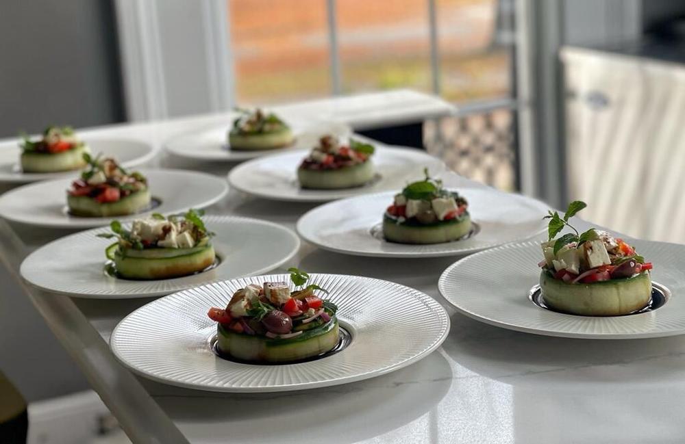Eight small plates are shown with a type of salad on each plate.