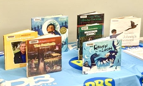 Books about Native American tribes and culture sit on a GPB Education + PBS KIDS co-branded tablecloth
