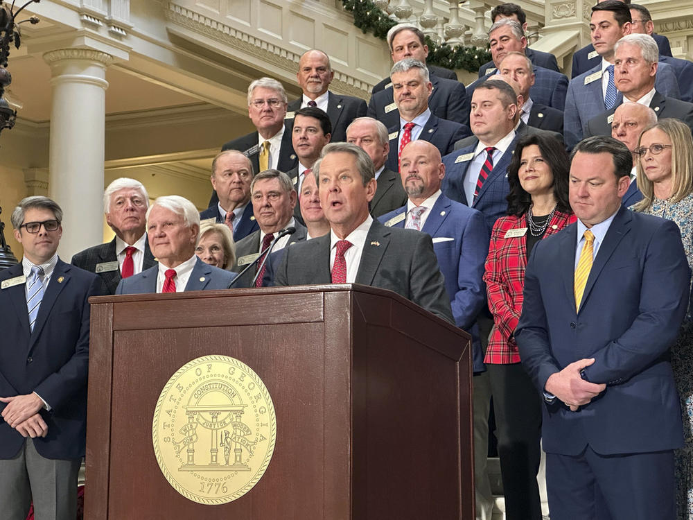 Georgia Gov. Brian Kemp, flanked by Republican lawmakers, speaks Monday, Dec. 4, 2023, at the Georgia Capitol in Atlanta. Kemp and Republican legislators want to make a further cut to Georgia's state income tax rate in the 2024 legislative session.
