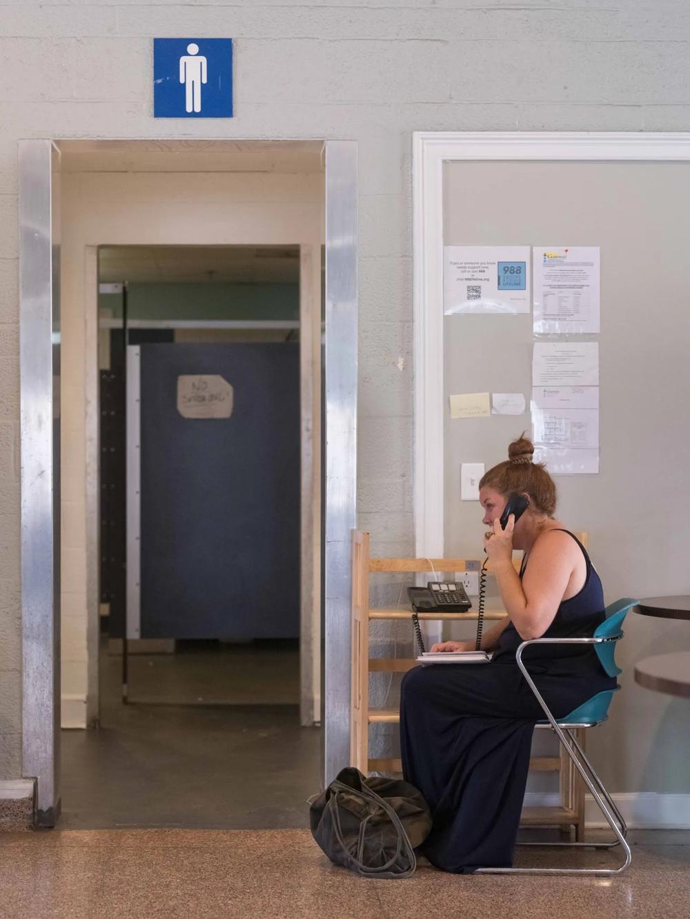 Mindy Carter takes advantage of the quietness at The Well to call loved ones and to look for a place to stay for the night. Credit: Justin Taylor/The Current