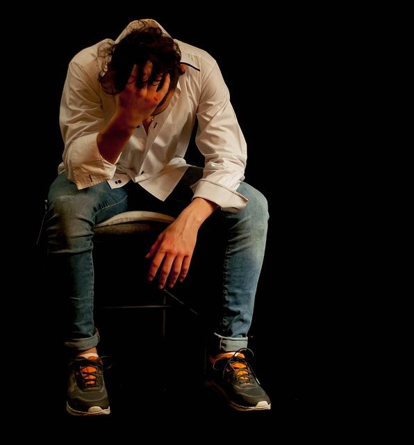 A dejected or tired teenager sits with his head in his hand