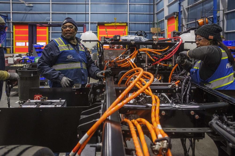 Janekia Corbin of Roberta, right, Arthur Cooper, center, of Fort Valley and Vonnie Jackson, left, of Macon, work to wire the motor of a Blue Bird electric school bus to its six battery packs on the Blue Bird EV bus production line in Fort Valley. 
