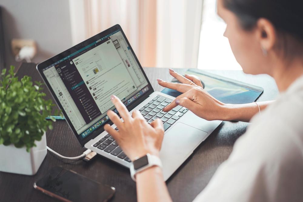 A woman types on her laptop on a table at home.