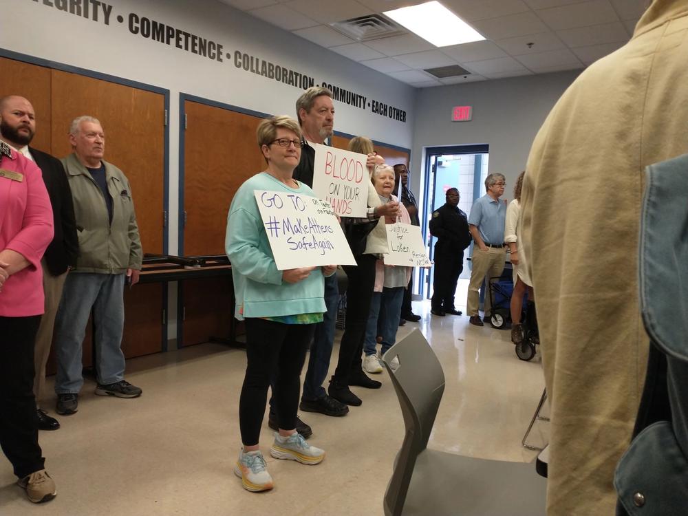 Protesters hold up signs at a press conference by Athens-Clarke County Mayor Kelly Girtz on Feb. 28, 2024.