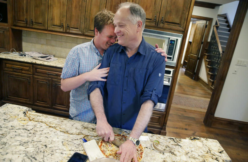 A son hugs his father in a kitchen