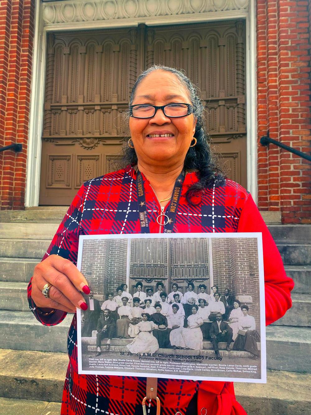 Carolyn Hensley, the church historian at Saint James A.M.E. Church in Columbus, Georgia, holds a photograph of the 1905 faculty of the church’s school. 02/16/2024 Mike Haskey mhaskey@ledger-enquirer.com  