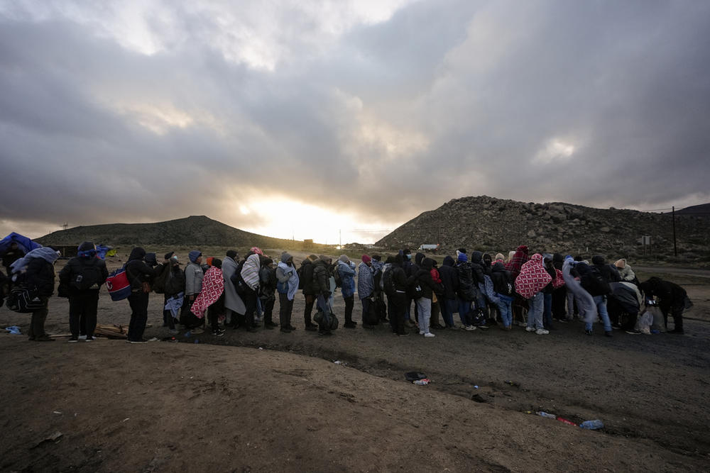 Asylum-seeking migrants line up in a makeshift, mountainous campsite to be processed after crossing the border with Mexico, Friday, Feb. 2, 2024, near Jacumba Hot Springs, Calif.  (AP Photo/Gregory Bull, File)