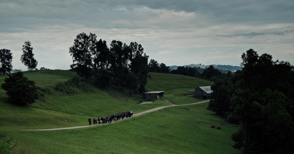 Funeral procession heads to the top of a hill to conduct a funeral for King Coal