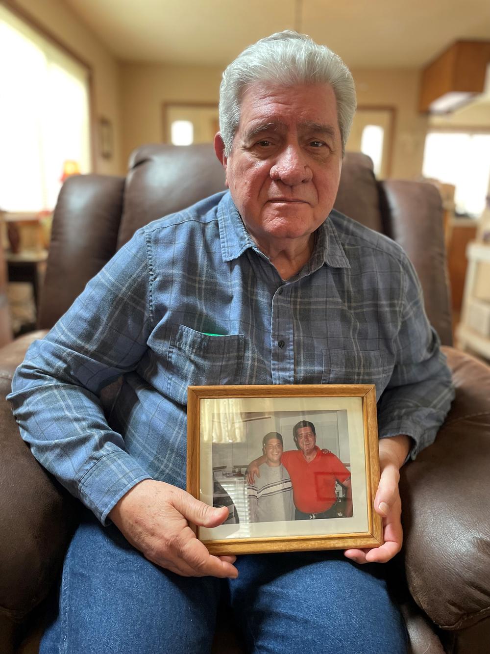 Matthew Pesce holds a framed photo of him and his son, who died by suicide.